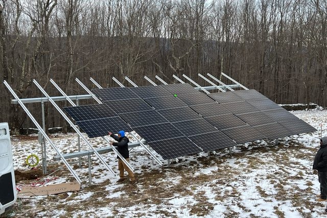 Crew mounting solar panels in light snow