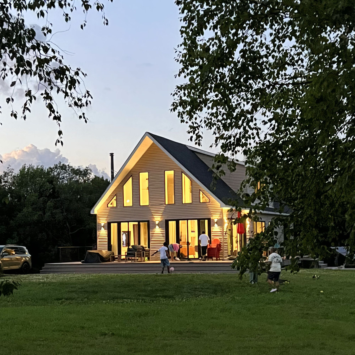 SOL glowing at dusk with guests on the lawn