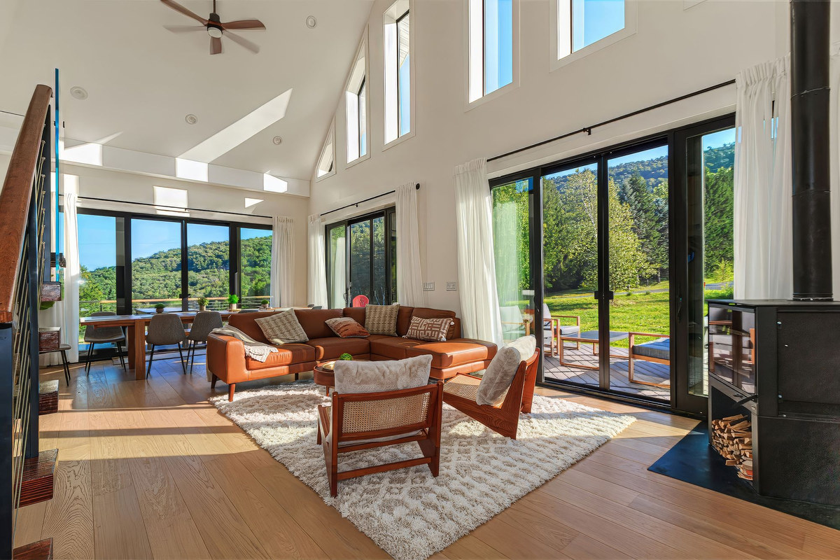 Great room with double-height windows, leather sectional and wood stove